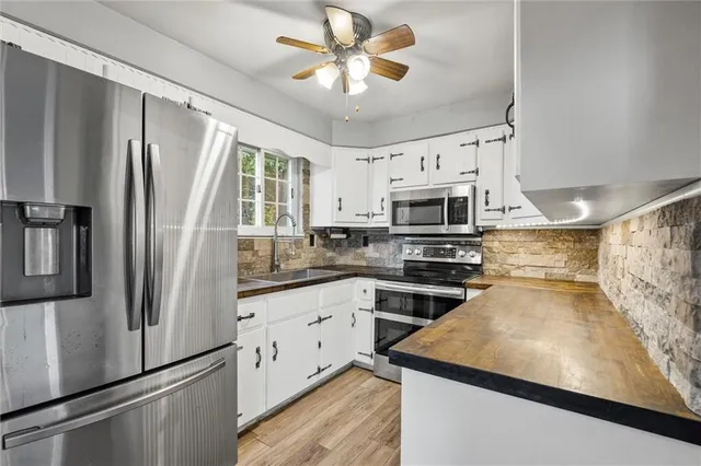 a kitchen with stainless steel appliances granite countertop a refrigerator a stove a sink and white cabinets
