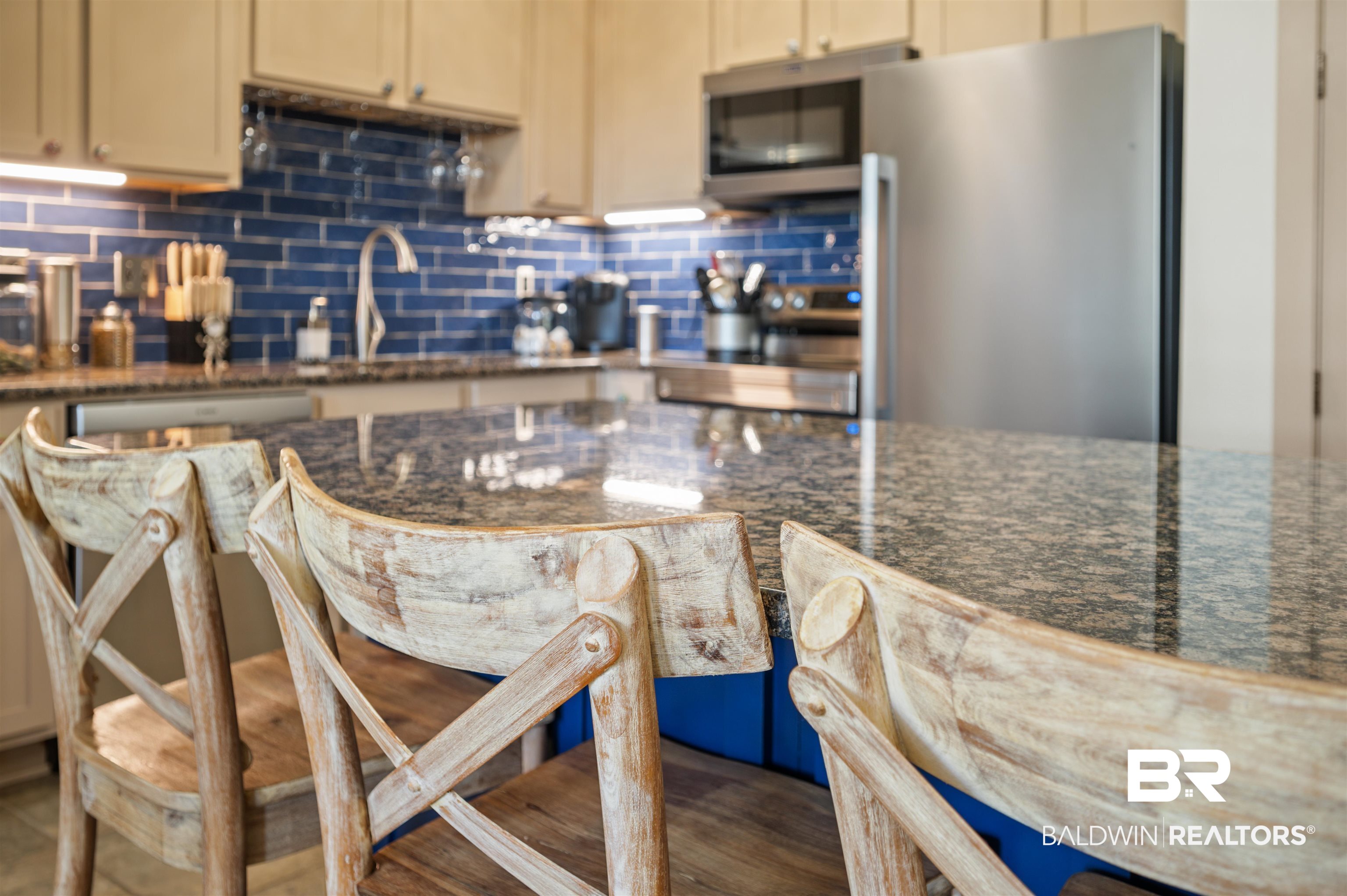 1430 Regency Road, Unit B202 Gulf Shores, AL 36542 - Photo 4 of 33 Kitchen featuring stainless steel appliances, a sink, backsplash, dark stone countertops, and a kitchen bar