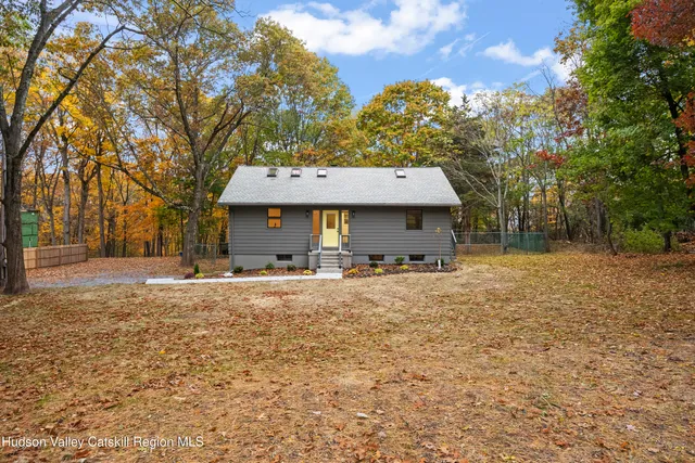 a view of a house with a yard and large tree