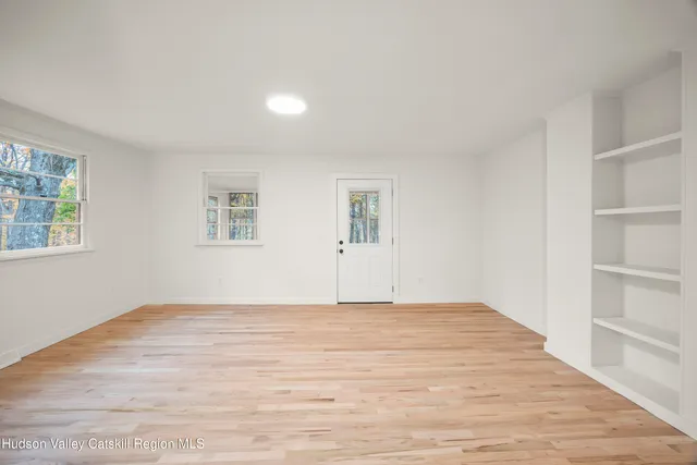 a view of an empty room with wooden floor and a window