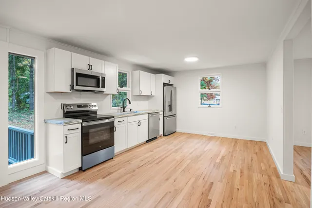 a kitchen with granite countertop a stove top oven a sink dishwasher and a refrigerator with wooden floor