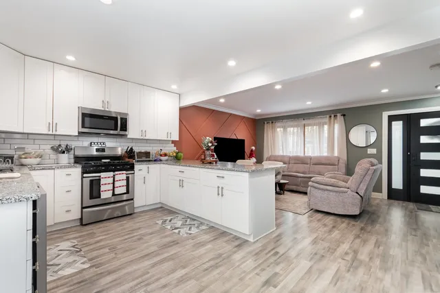 a kitchen with granite countertop a stove top oven a sink dishwasher a dining table and chairs with wooden floor