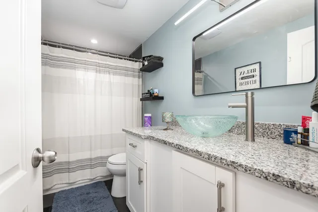 a bathroom with a granite countertop sink a toilet and a shower
