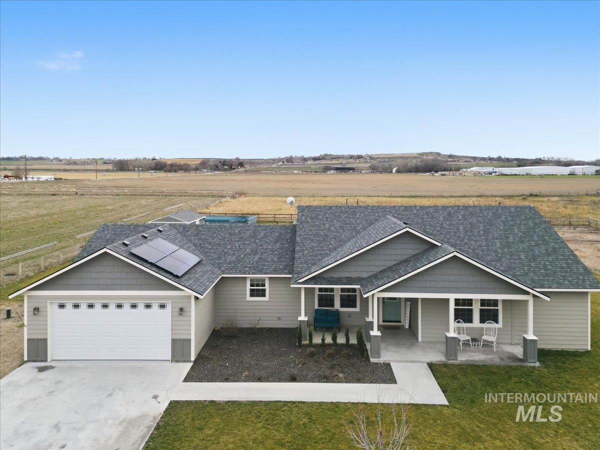 26453 Ustick Road Wilder, ID 83676 - Photo 1 of 1 Craftsman-style home with roof with shingles, solar panels, a view of countryside, and a front yard