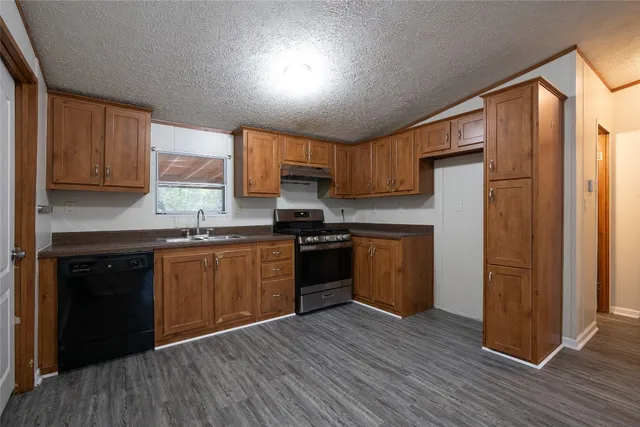 a kitchen with granite countertop wooden floors stainless steel appliances and sink