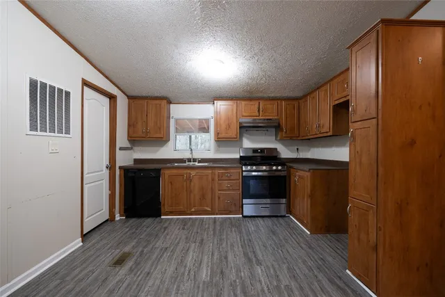 a kitchen with granite countertop wooden floors stainless steel appliances and cabinets