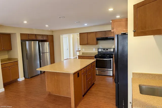 a kitchen with stainless steel appliances granite countertop a refrigerator a sink a stove and oven