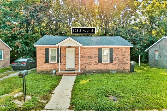 a front view of a house with a yard and trees