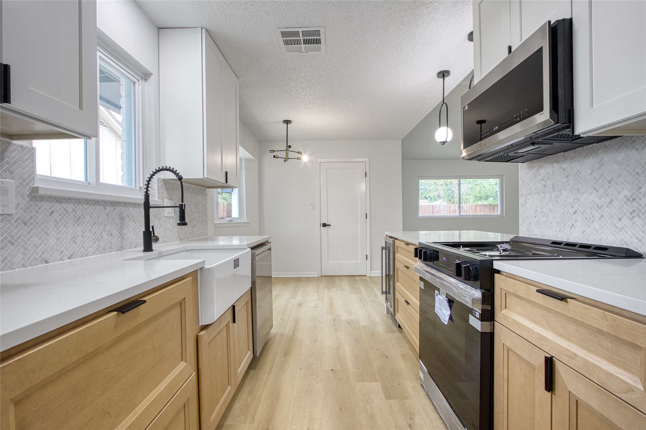 5802 Chrystell Lane Houston, TX 77092 - Photo 4 of 17 a kitchen with stainless steel appliances a sink dishwasher a stove and a microwave oven with wooden floor
