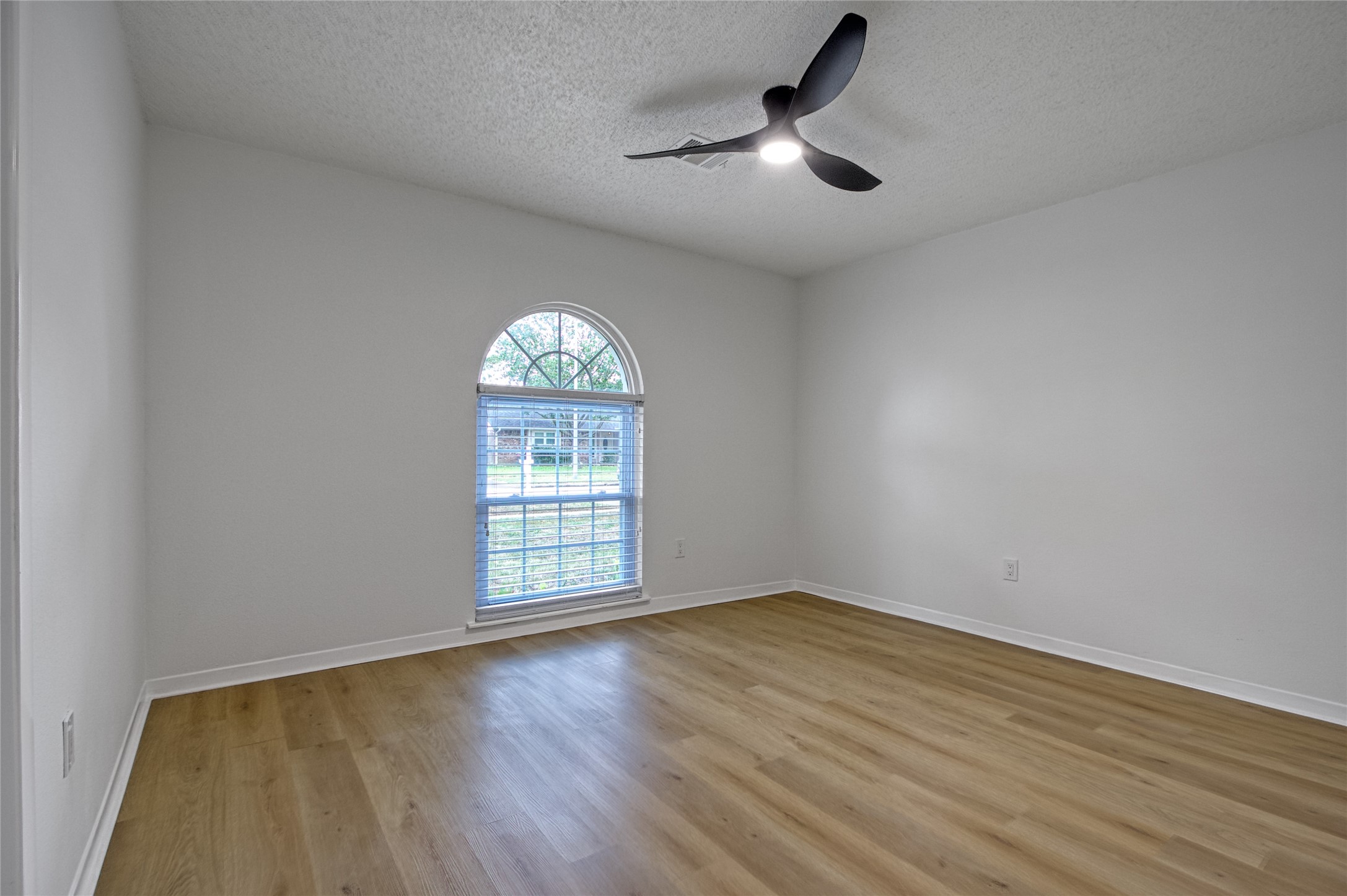 5802 Chrystell Lane Houston, TX 77092 - Photo 9 of 17 an empty room with wooden floor fan and windows