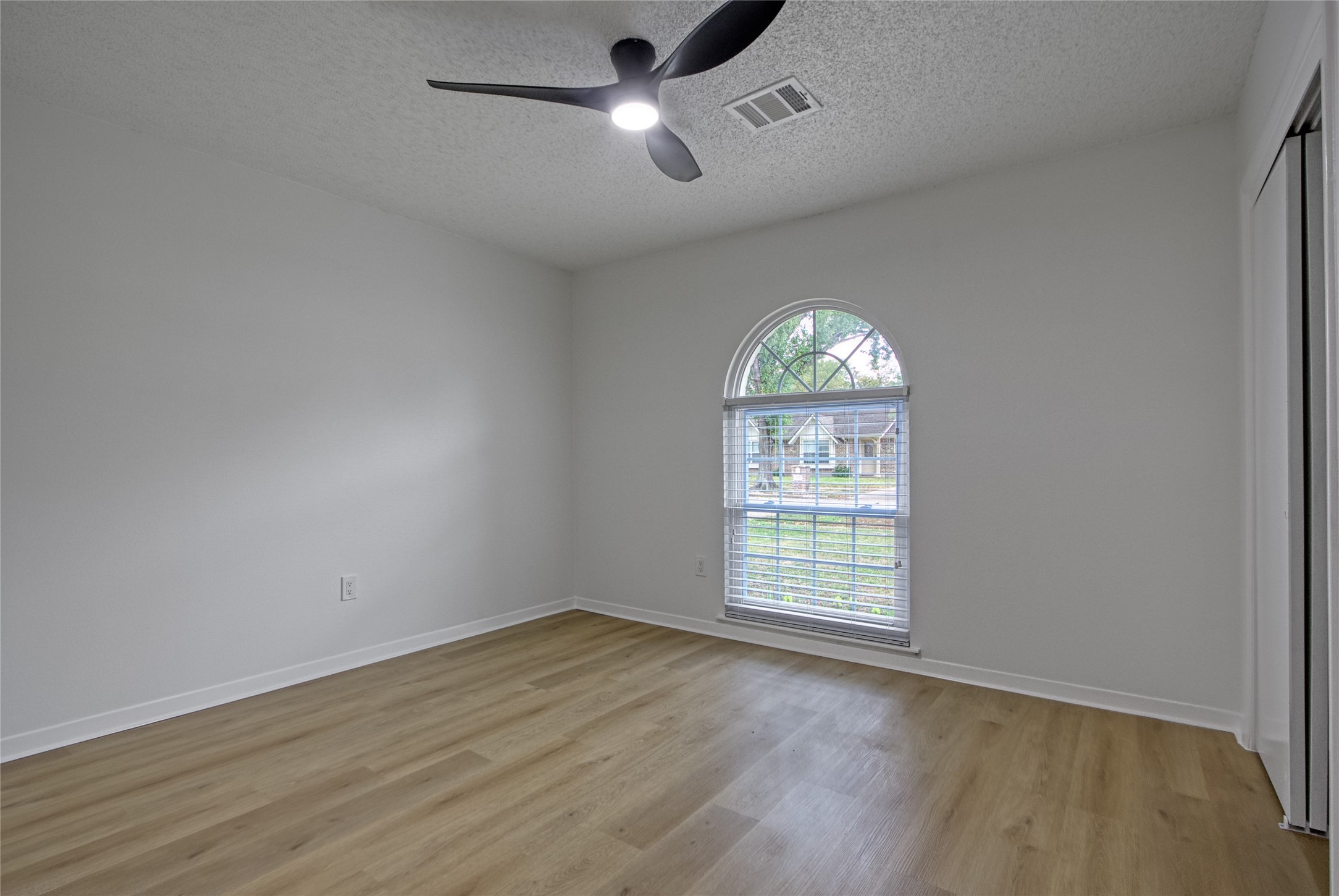 5802 Chrystell Lane Houston, TX 77092 - Photo 10 of 17 an empty room with wooden floor chandelier fan and windows