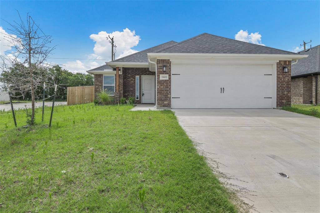 Ranch-style home featuring a garage, brick siding, concrete driveway, and roof with shingles