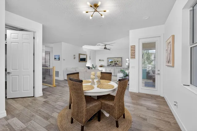 a kitchen with a dining table chairs wooden floor cabinets appliances and a window