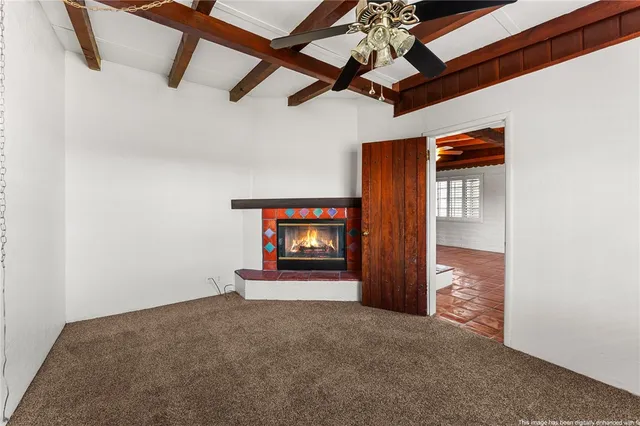 a view of an empty room with a fireplace and a ceiling fan