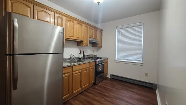 a kitchen with stainless steel appliances granite countertop a refrigerator a stove a sink and a window
