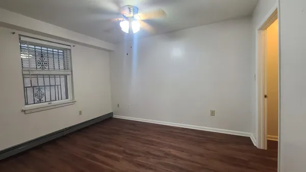 a view of an empty room with wooden floor and a window
