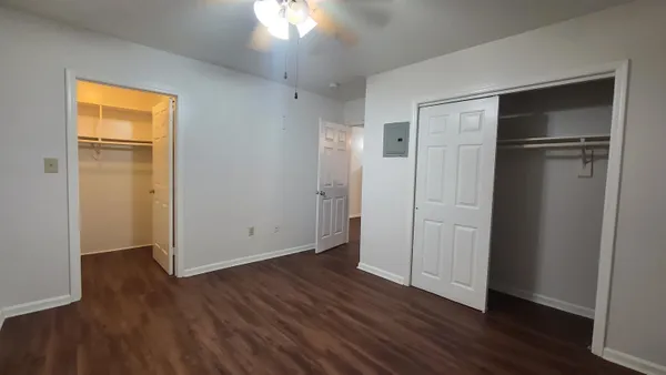 an empty room with wooden floor cabinet and windows