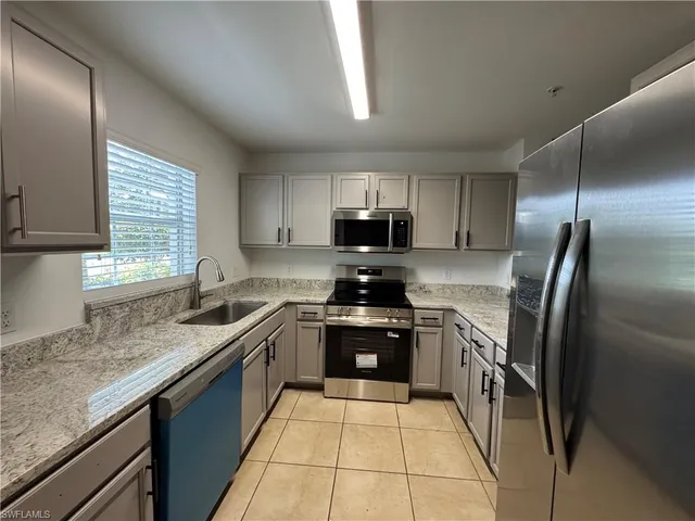 a kitchen with stainless steel appliances granite countertop a sink stove microwave and refrigerator