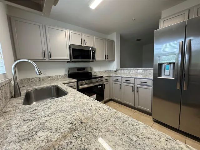 a kitchen with granite countertop a sink stainless steel appliances and cabinets