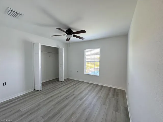 a view of an empty room with a window and wooden floor