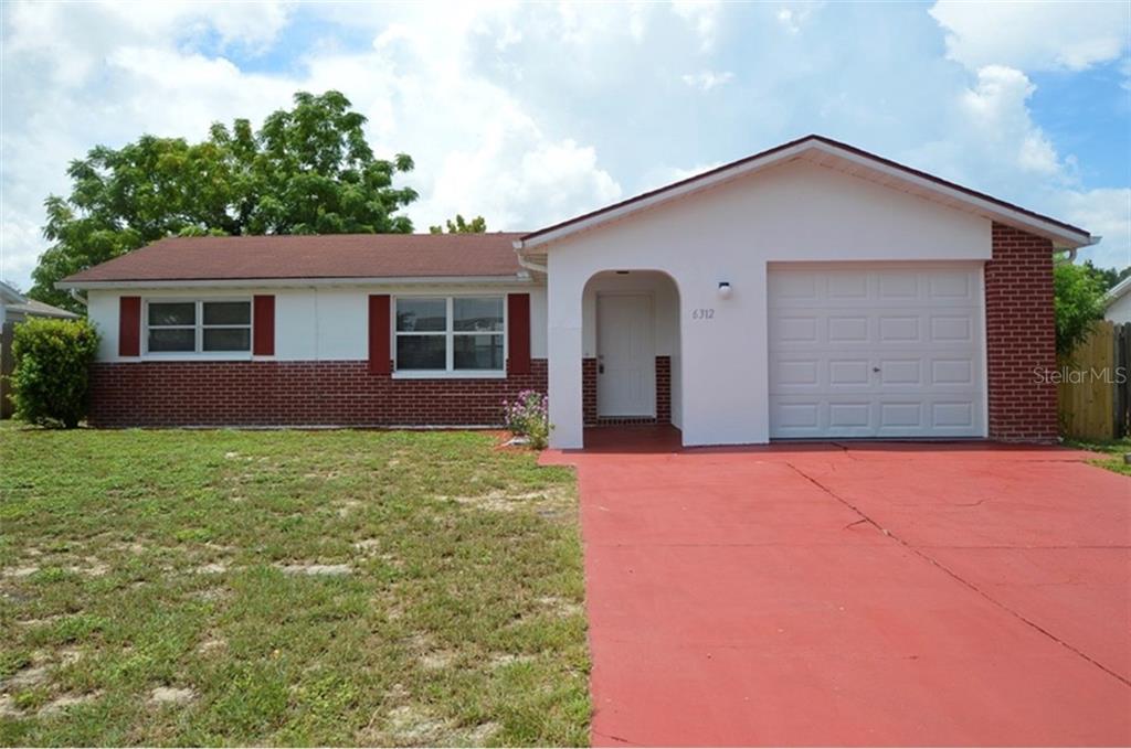 6312 Baldwyn Avenue New Port Richey, FL 34653 - Photo 1 of 1 a front view of house with yard and trees