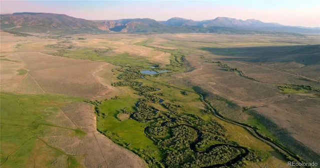 a view of a lush green field with mountains in the background