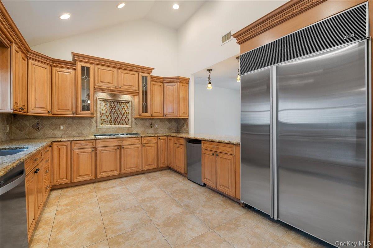 33 Fleets Cove Road Huntington, NY 11743 - Photo 9 of 42 Kitchen featuring stainless steel appliances, hanging light fixtures, light stone countertops, high vaulted ceiling, and tasteful backsplash