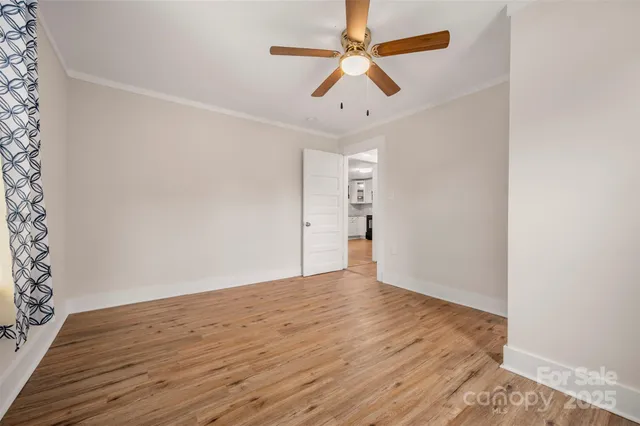 an empty room with wooden floor ceiling fan and window