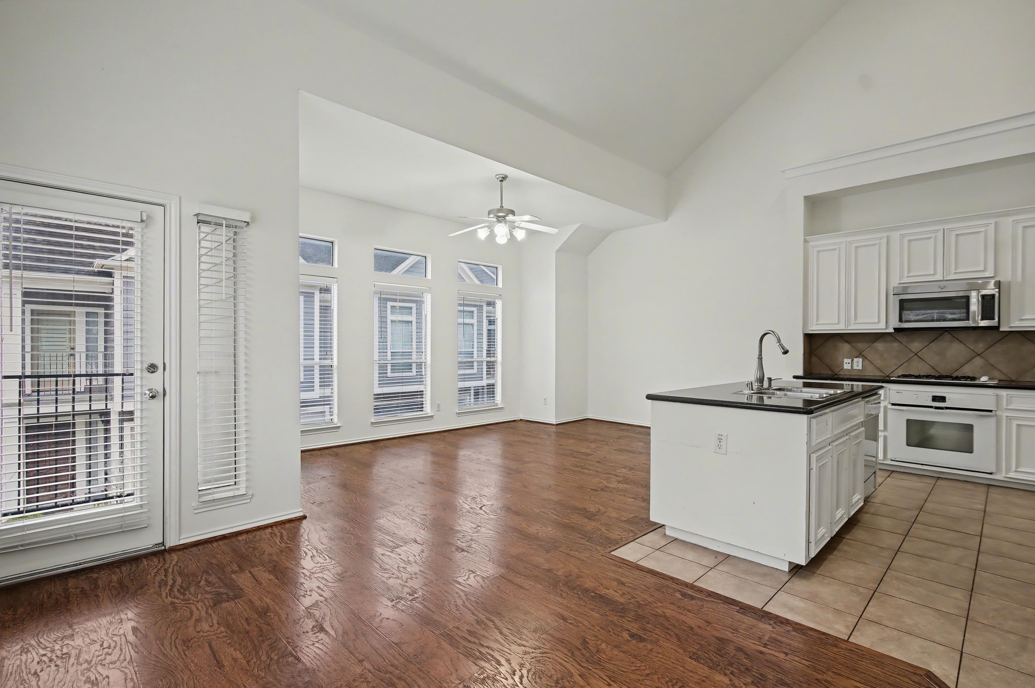 2416 Charleston Street, Unit A Houston, TX 77021 - Photo 2 of 24 a kitchen with granite countertop a stove top oven a sink dishwasher and white cabinets with wooden floor