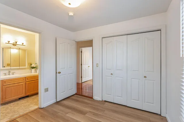 a view of an empty room with wooden floor and a bathroom