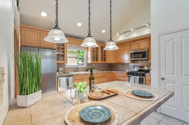 a kitchen with stainless steel appliances granite countertop a stove a kitchen island a table and chairs
