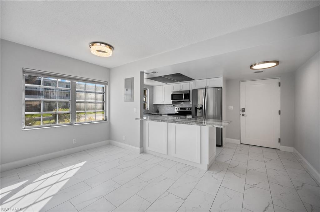 666 3rd Street South, Unit 106 Naples, FL 34102 - Photo 4 of 32 a kitchen with stainless steel appliances a refrigerator sink and cabinets