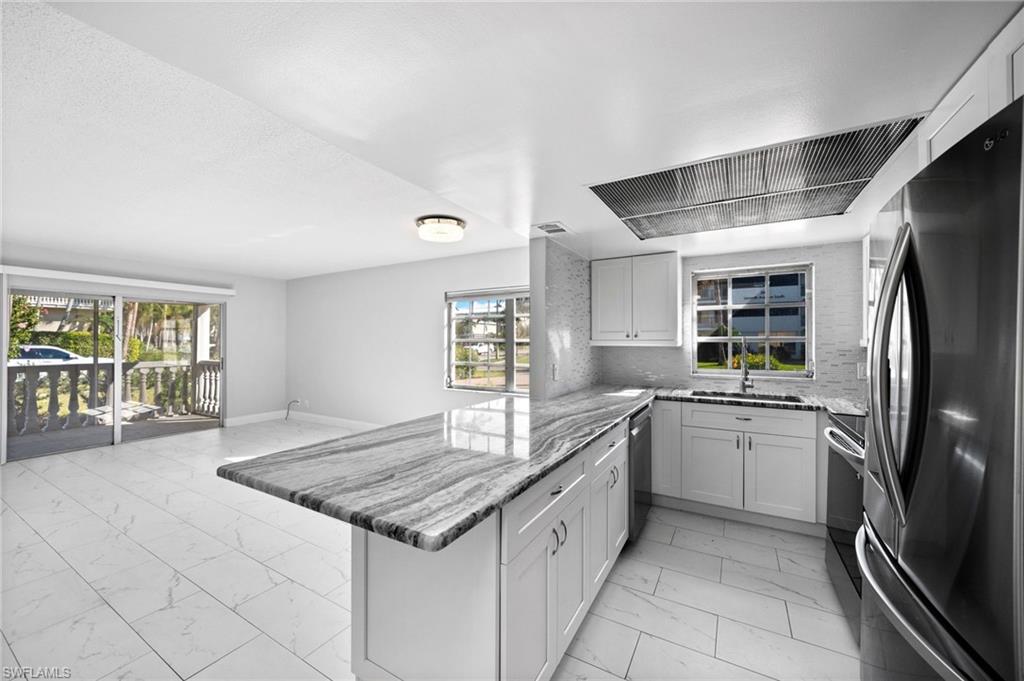 666 3rd Street South, Unit 106 Naples, FL 34102 - Photo 5 of 32 a kitchen with stainless steel appliances granite countertop a sink stove and refrigerator