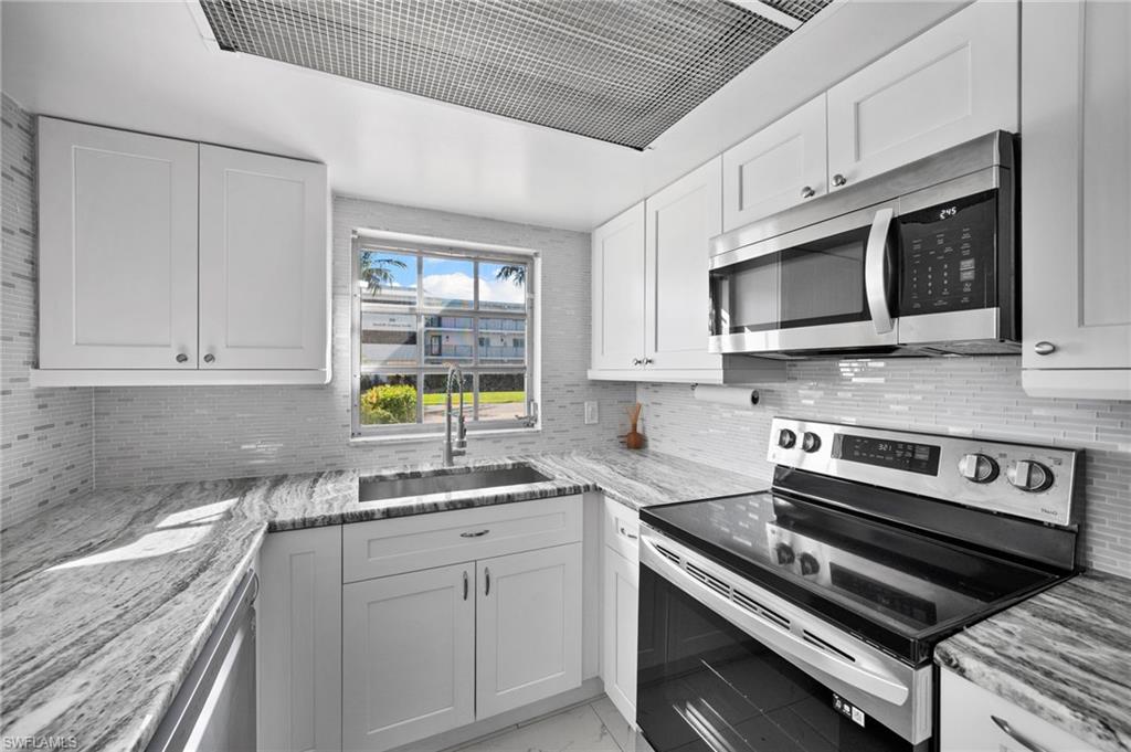 666 3rd Street South, Unit 106 Naples, FL 34102 - Photo 6 of 32 a kitchen with stainless steel appliances a stove microwave and cabinets