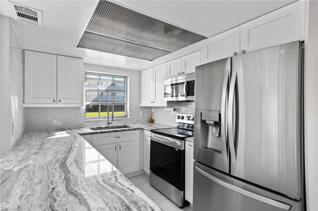 666 3rd Street South, Unit 106 Naples, FL 34102 - Photo 7 of 32 a kitchen with stainless steel appliances a refrigerator sink and microwave