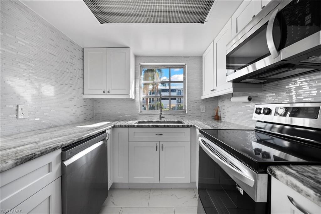 666 3rd Street South, Unit 106 Naples, FL 34102 - Photo 8 of 32 a kitchen with stainless steel appliances granite countertop a sink stove oven and white cabinets