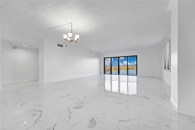 en empty room with windows and chandelier