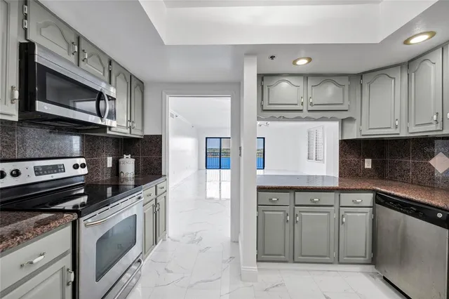 a kitchen with granite countertop a stove microwave and refrigerator
