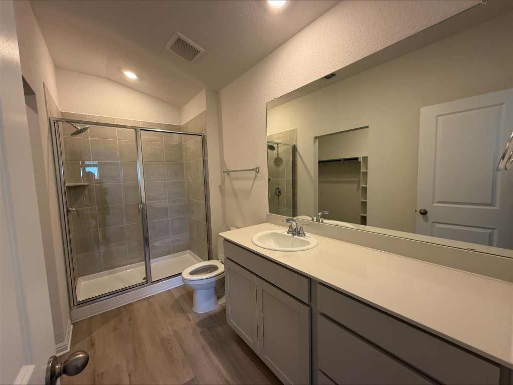 105 Honey Bee Road Jarrell, TX 76537 - Photo 6 of 9 Full bathroom with a shower stall, dark wood-type flooring, a spacious closet, vanity, and vaulted ceiling