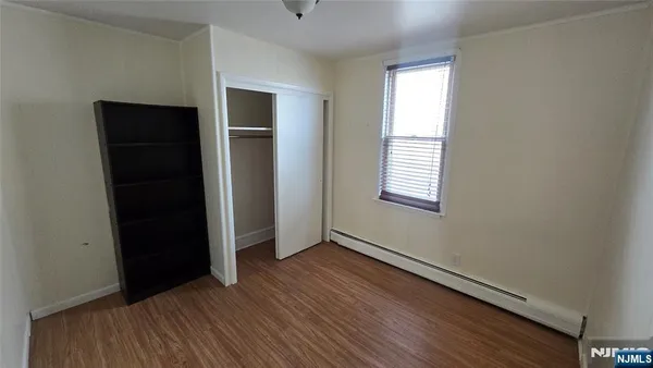 an empty room with wooden floor closet and windows