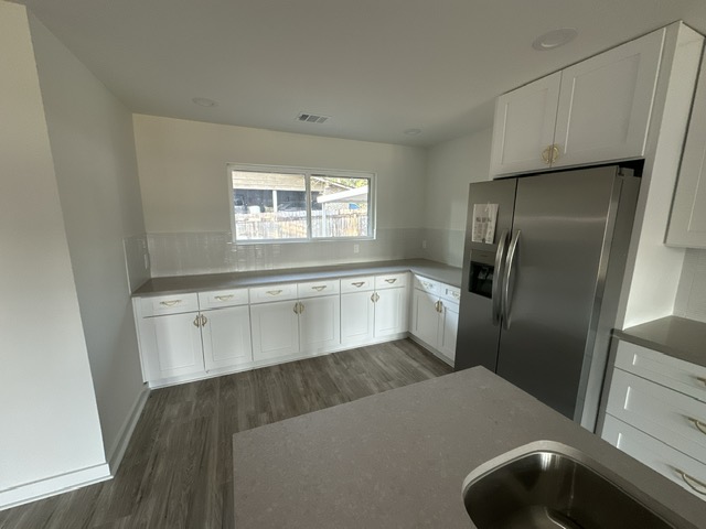 2101 Vanderbilt Lane Austin, TX 78723 - Photo 14 of 25 Kitchen with white cabinets, stainless steel fridge, dark wood-type flooring, and backsplash