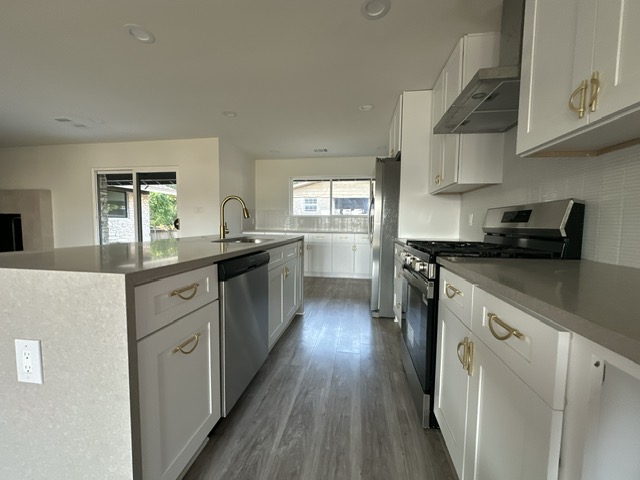 2101 Vanderbilt Lane Austin, TX 78723 - Photo 15 of 25 Kitchen with appliances with stainless steel finishes, white cabinets, wall chimney range hood, recessed lighting, and dark wood finished floors