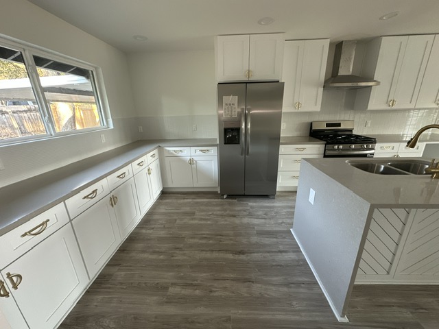2101 Vanderbilt Lane Austin, TX 78723 - Photo 9 of 25 Kitchen featuring white cabinets, stainless steel appliances, wall chimney range hood, and dark wood-style flooring