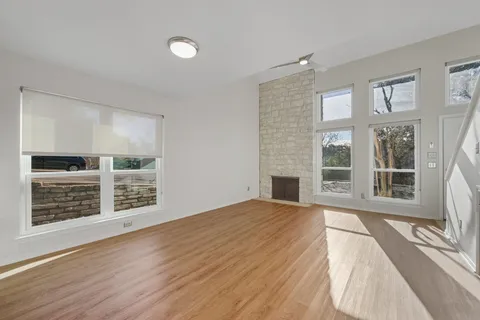 a view of an empty room with a window and wooden floor