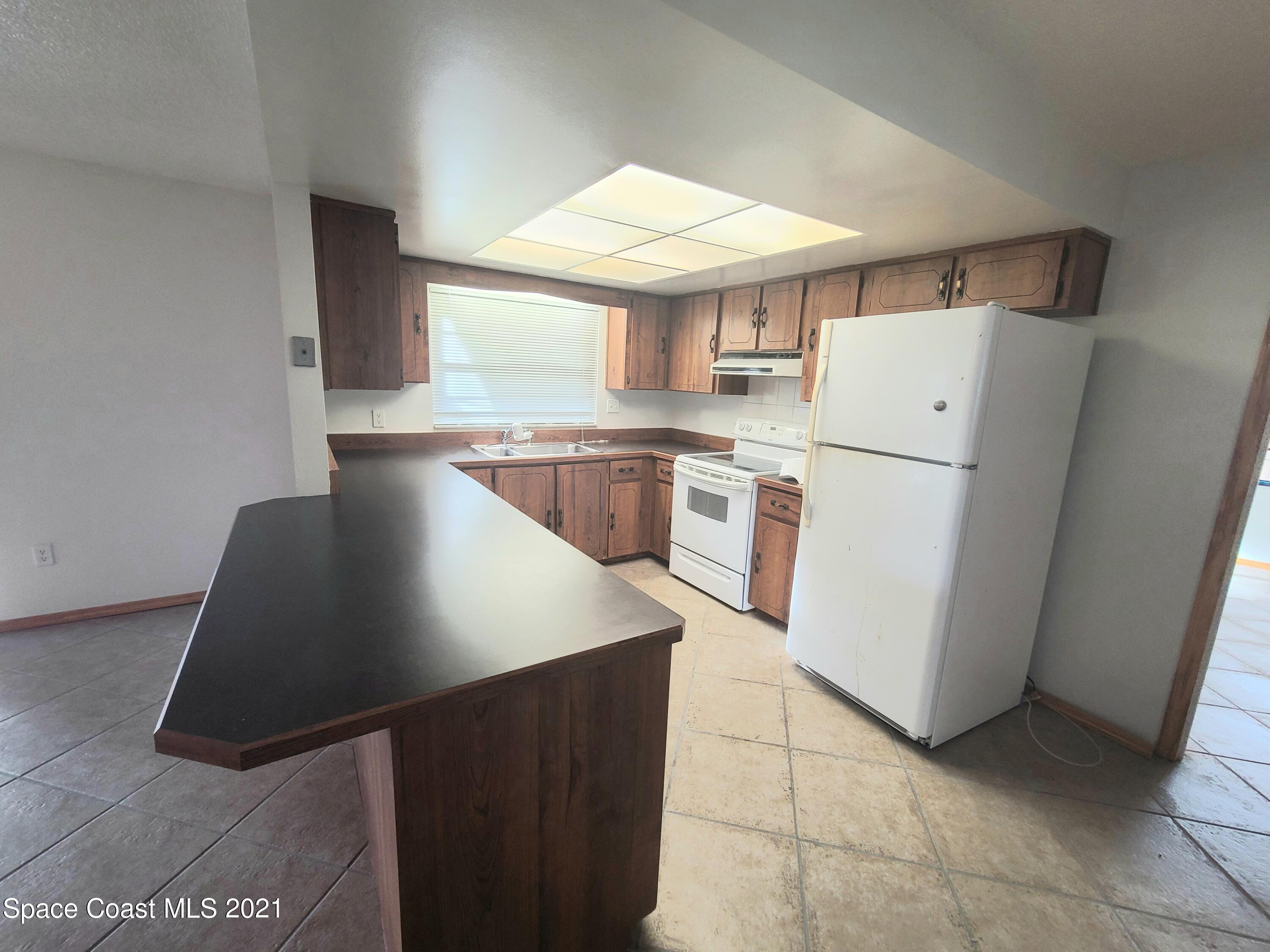 292 Chase Road Cocoa, FL 32927 - Photo 8 of 17 a kitchen with a refrigerator and a stove top oven