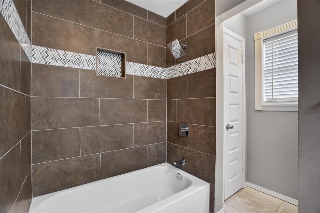 6609 Genoa Road Fort Worth, TX 76116 - Photo 26 of 40 Bathtub with subway tile surround featuring a decorative mosaic accent band and a recessed shower niche