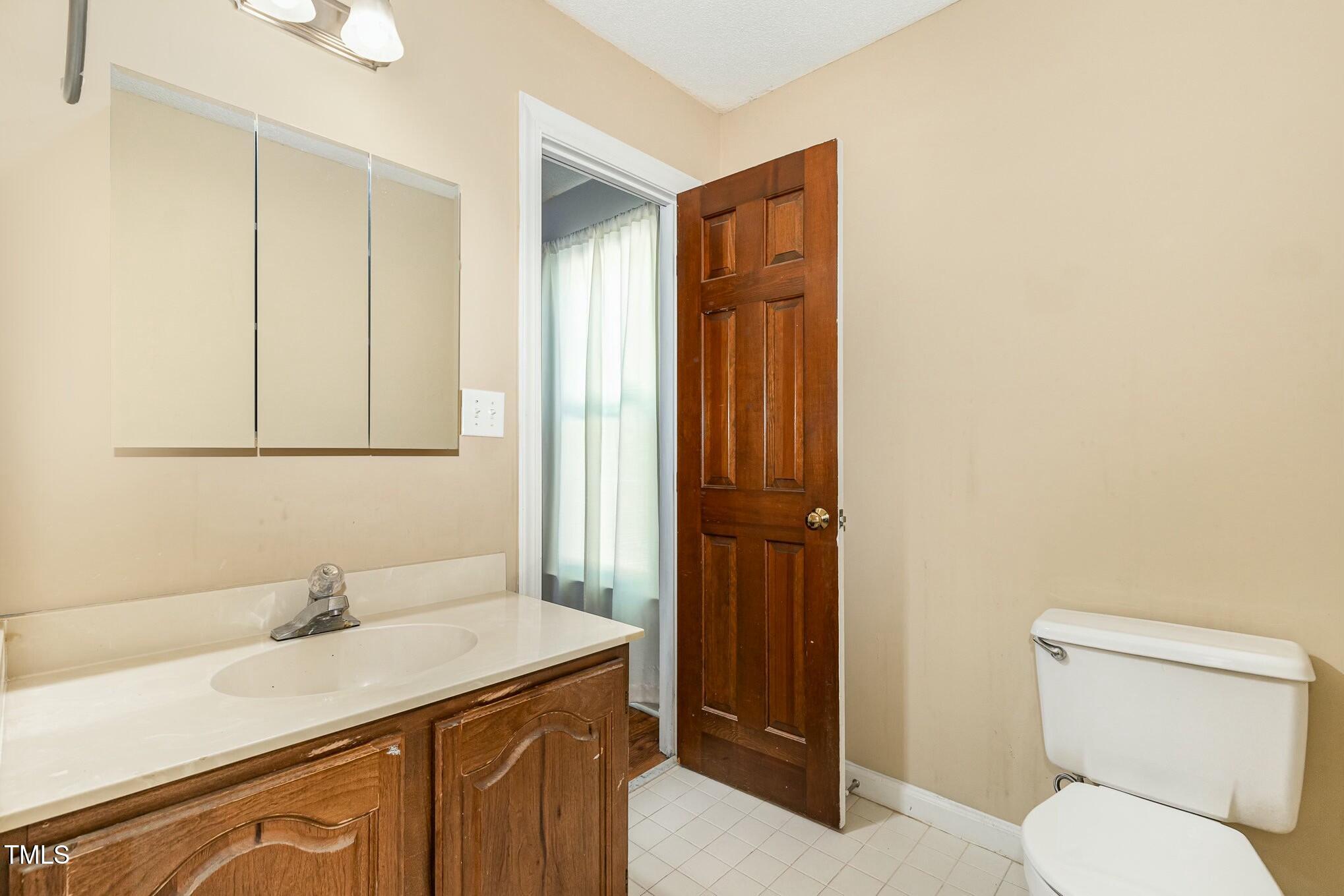 3109 East Folkestone Place Raleigh, NC 27604 - Photo 14 of 25 a bathroom with a granite countertop sink toilet and mirror