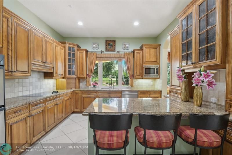2515 Montclaire Circle Weston, FL 33327 - Photo 7 of 51 a kitchen with granite countertop a table chairs stove and cabinets