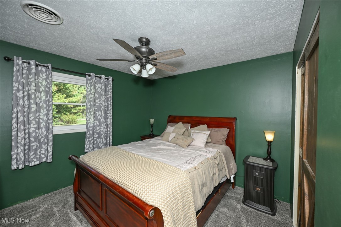 18047 Racine Road Marshallville, OH 44645 - Photo 8 of 10 Bedroom featuring a textured ceiling, dark carpet, and a ceiling fan