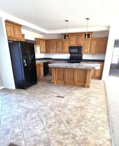 a kitchen with stainless steel appliances kitchen island granite countertop a refrigerator and a stove top oven